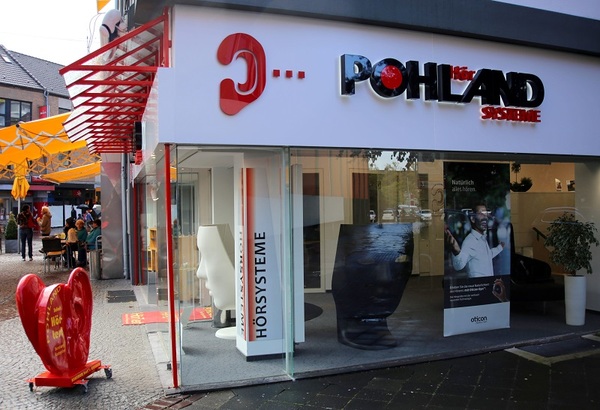 Modernes Hörakustik-Fachgeschäft mit Glasfassade und auffälligem POHLAND-Hörsysteme-Logo.